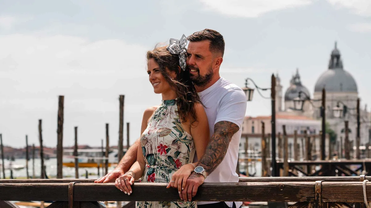 Couple posing for a piazza san marco photoshoot in Venice with the basilica behind them at sunrise
